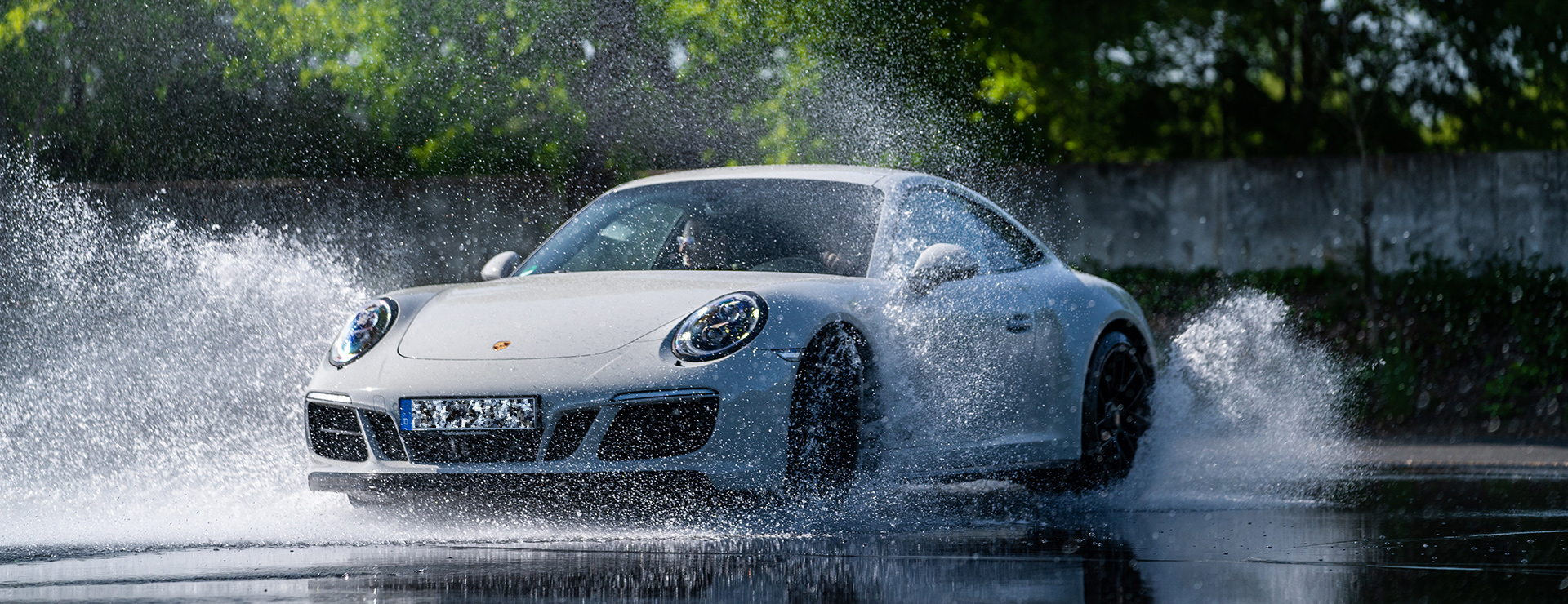 Ein Porsche Sportwagen fährt auf einer nassen Strecke.